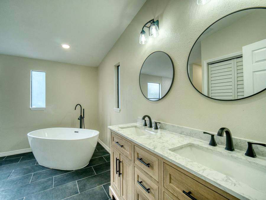 Renovated bathroom with freestanding soaking tub, double vanity and slate tile floor