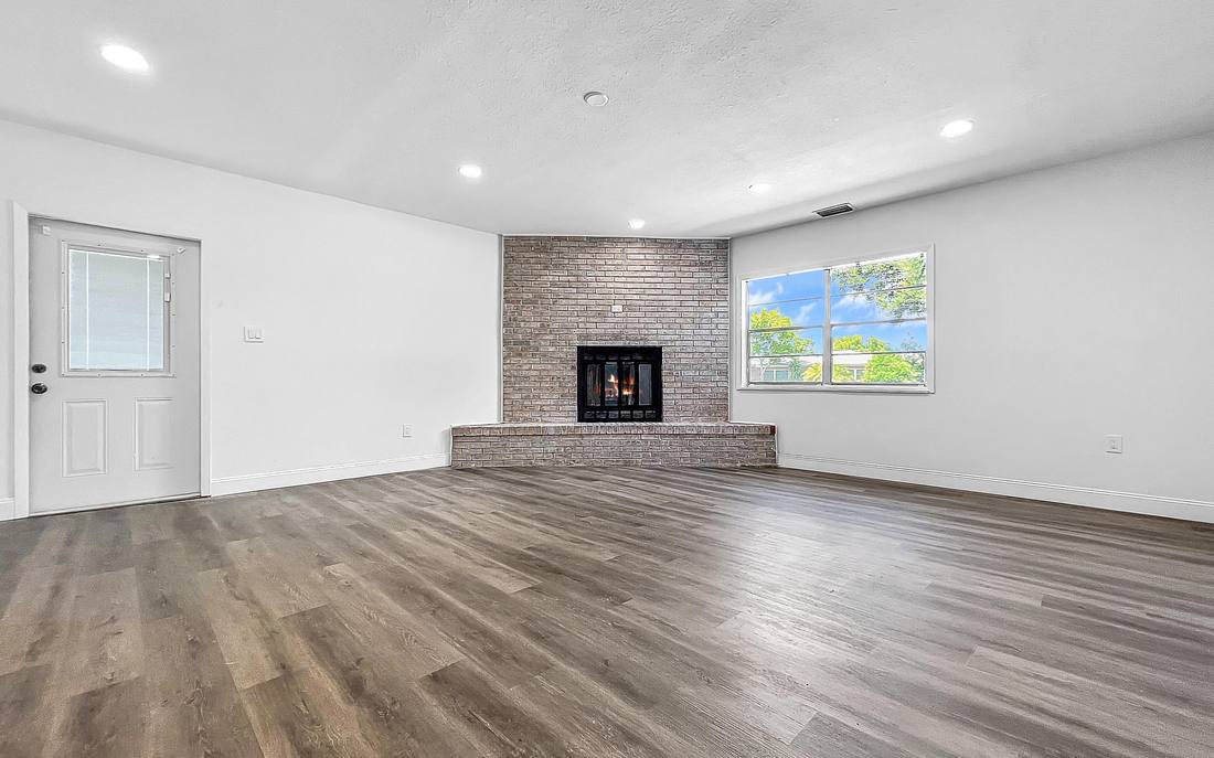 Renovated living room with brick fireplace, recessed lighting and new luxury vinyl plank flooring